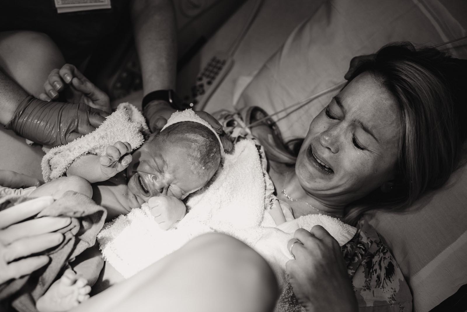 mother cries holding her baby for the first time after birth