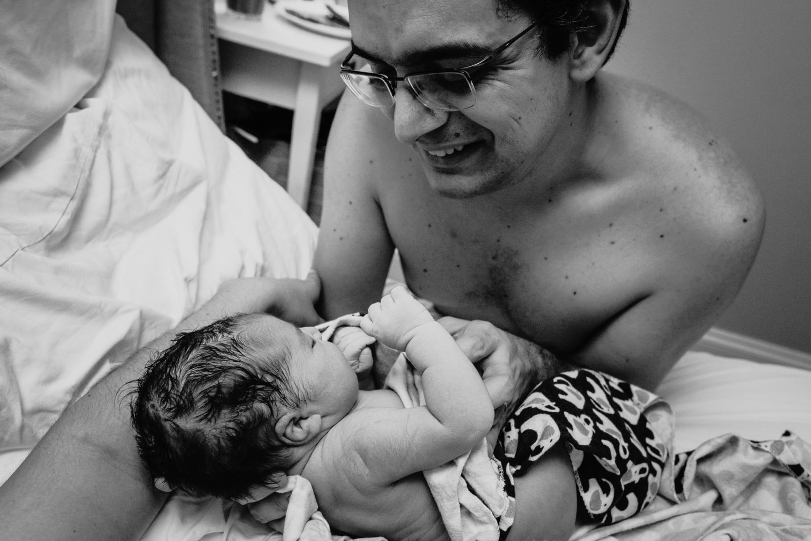 father smiles down at his newborn daughter
