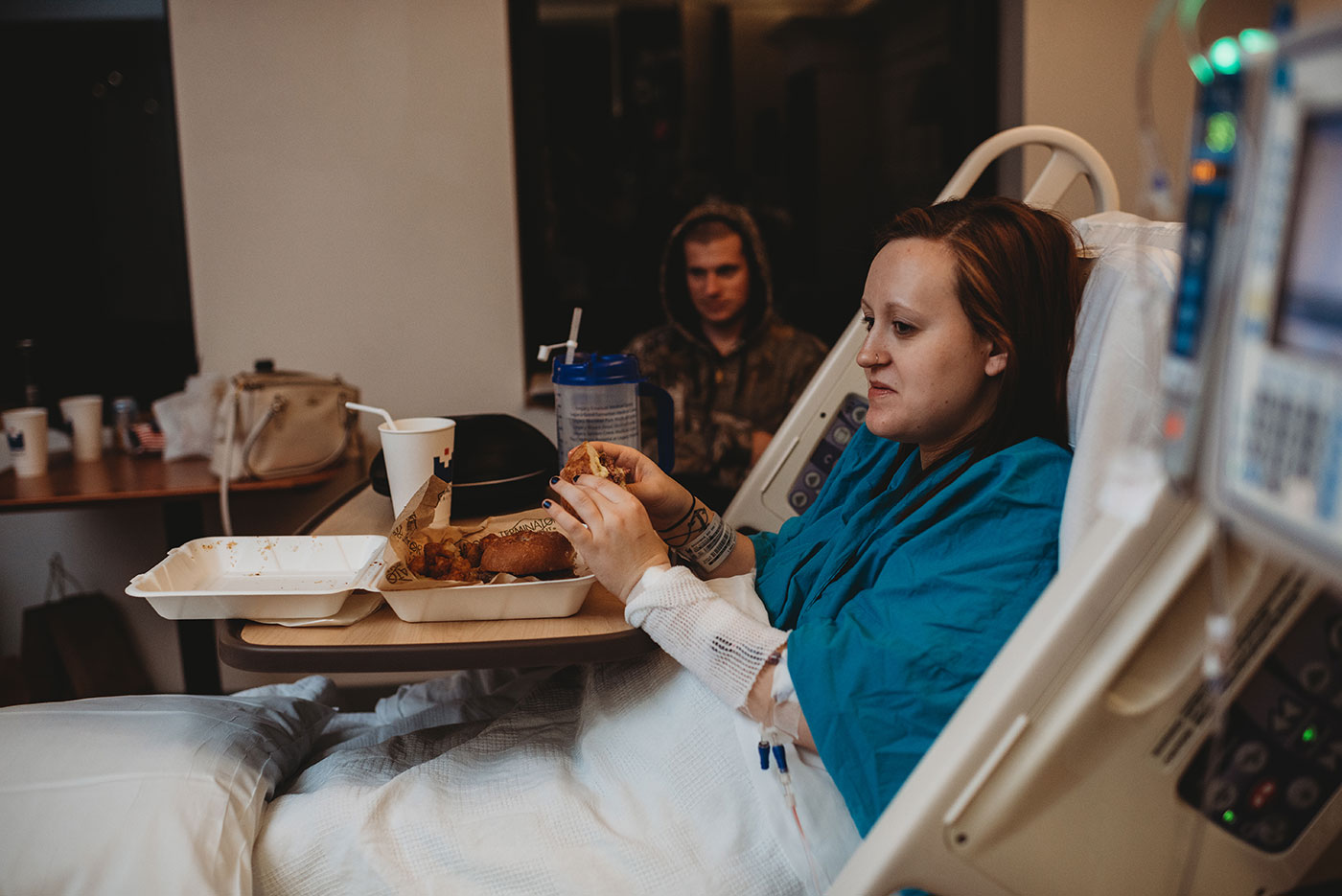 mom sits up in bed to eat her first meal after giving birth