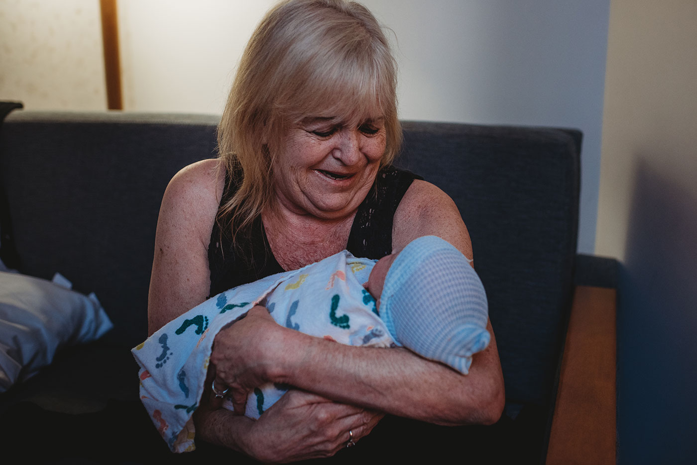 smiling great-grandmother holds her newborn grandson for the first time