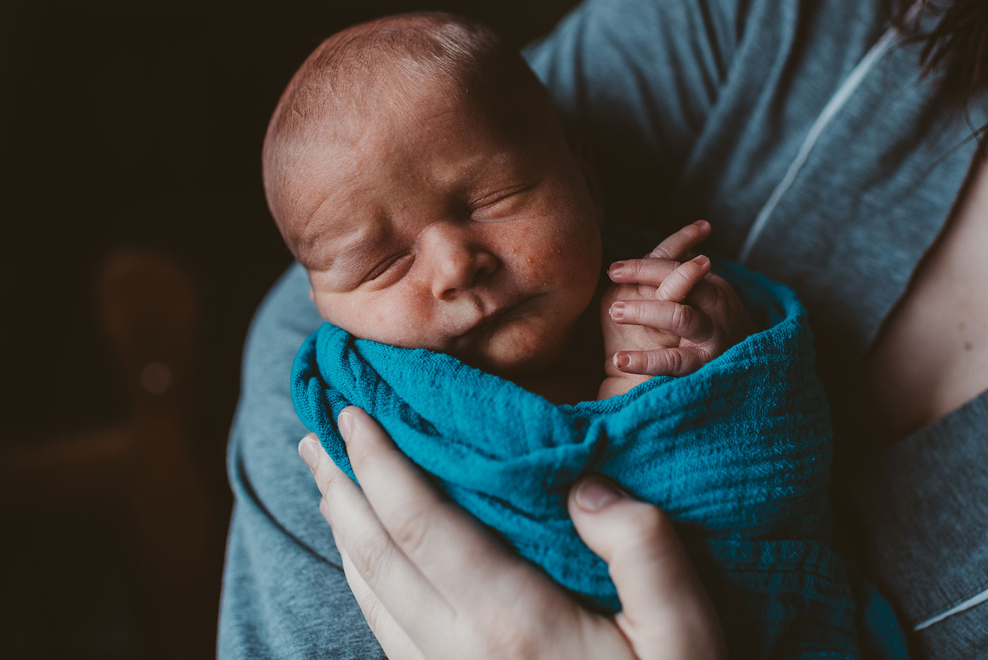 newborn baby boy swaddled in a blue blanket