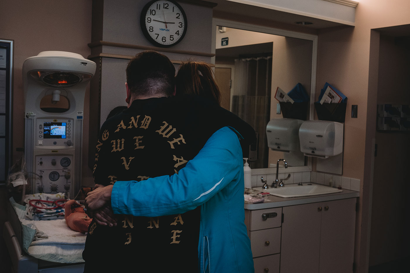 brother and sister hug whiile looking at newborn baby boy in the hospital in Portland