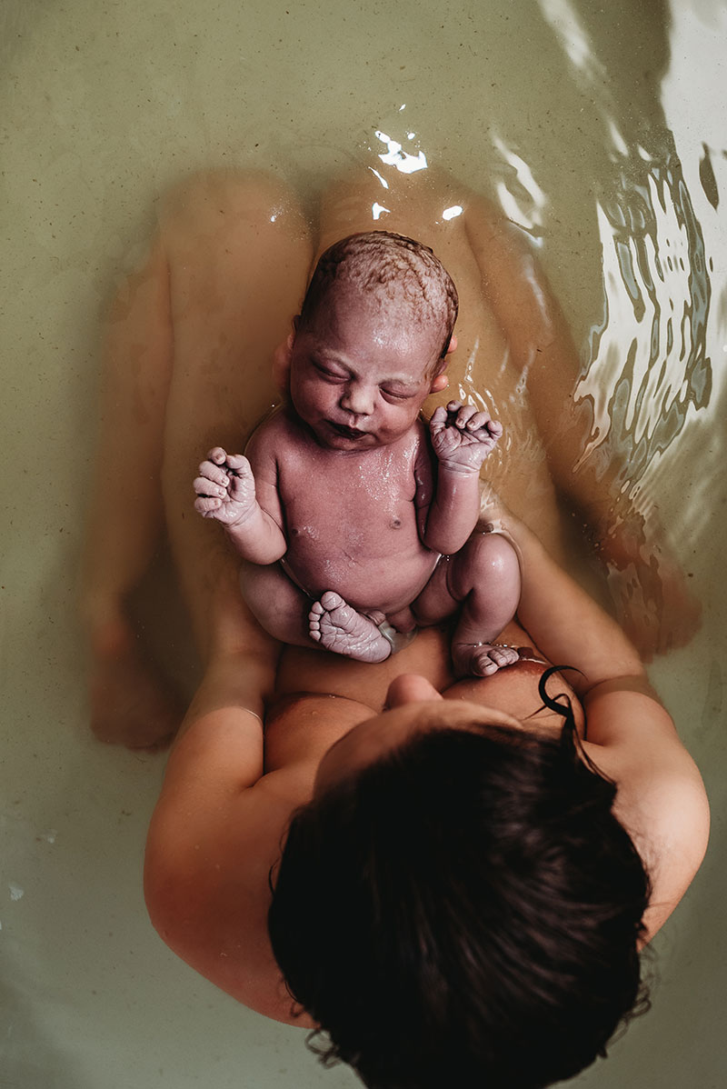 mother holding her newborn in the water immediately after birth