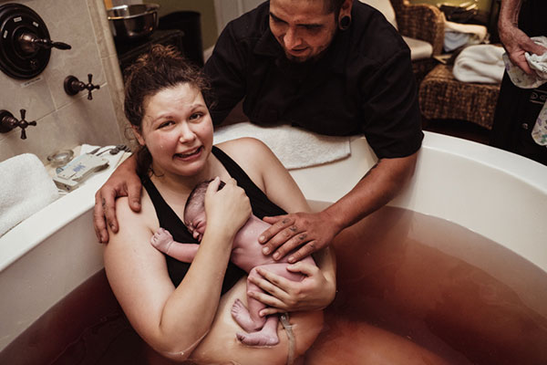 crying mom holds her baby for the first time after a water birth